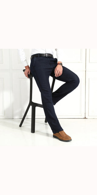 Navy blue velvet jeans with stylish leather belt on model against white background.