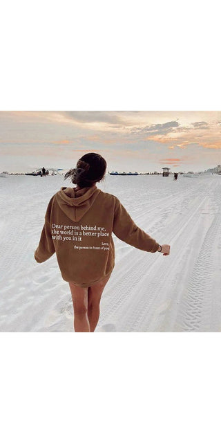 Cozy cotton hoodie with inspirational message, worn by person walking on serene, snowy landscape at sunset