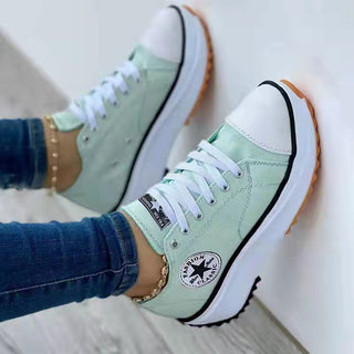 Trendy women's mint green canvas sneakers with thick soles and Converse logo, displayed on feet against a plain background.