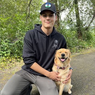 Smiling young man with a dog on wooded path