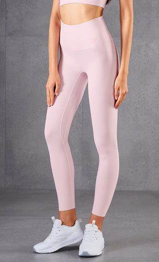 High-waisted peach-colored athletic leggings with a slim, body-hugging fit, designed for a comfortable and confident workout experience. Paired with white sneakers, this outfit showcases a modern, stylish activewear look.