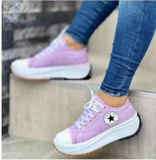 Purple lace-up casual sneakers with thick soles on a woman's feet.