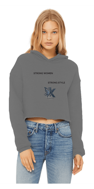 Stylish women's gray cropped hoodie with "Strong Women Strong Style" text and 'X' graphic design. The model is wearing a casual, fashion-forward outfit including the hoodie.
