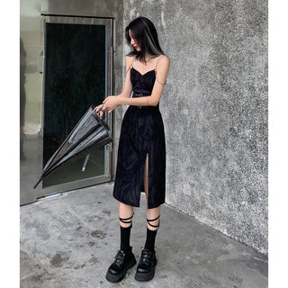 Elegant black lace suspender dress with high slit, styled with platform boots for a modern, edgy look against a concrete wall background.
