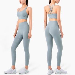Stylish fitness outfit featuring grey sports brassiere and coordinating leggings. The design showcases a cross-back strap detail on the bra and a sleek, body-hugging silhouette for the leggings. This trendy activewear set from the K-AROLE brand is perfect for a variety of fitness activities.
