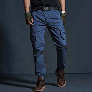 Stylish navy blue cargo pants with multiple pockets and tactical design elements, worn by a person with a black shirt and leather boots, showcasing a modern, rugged fashion style.