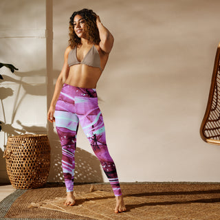Woman in vibrant printed yoga leggings from K-AROLE, a women's fashion sneaker brand, posing in a studio setting with natural light and woven decor elements.