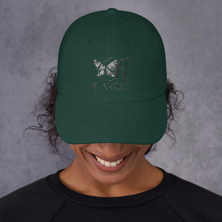 Stylish green dad hat with K-AROLE logo and butterfly design, worn by a smiling person against a gray background.