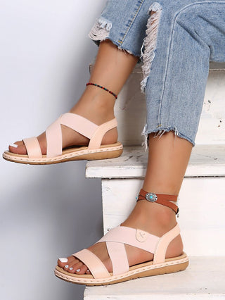 Elegant feminine sandals with criss-cross straps, showcased on a person's legs against a plain background.