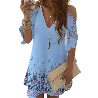 Fashionable blue cold-shoulder dress with floral print, worn with accessories like a necklace and a beige clutch bag.