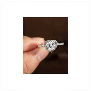 Elegant crystal heart-shaped wedding ring with sparkling diamond accents, showcased on a woman's hand against a dark background