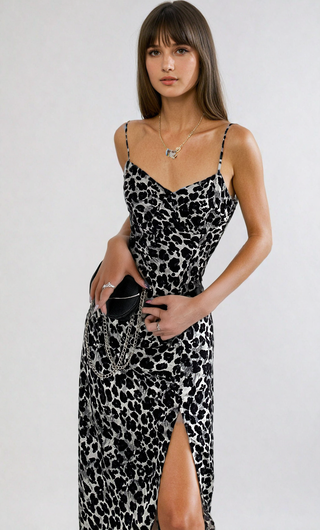 Stylish leopard print dress with spaghetti straps, slim fit, and thigh-high slit showcasing model's fashionable look.
