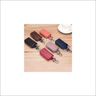 Stylish leather key holders in various colors arranged on a wooden surface. Compact and organized storage for car keys, wallets, and other small essentials. Featuring a sleek and modern design, these key pouches from the K-AROLE brand provide a practical and fashionable way to keep your daily accessories together.