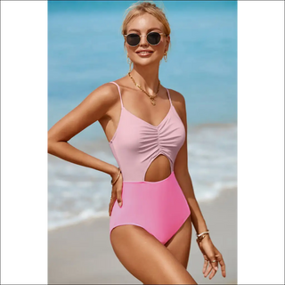 Stylish one-piece swimsuit with cutouts and spaghetti straps, worn by a smiling woman on a sunny beach.