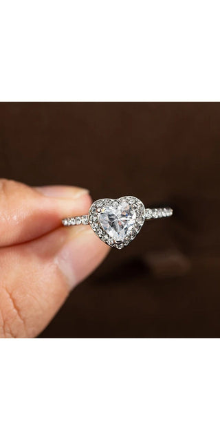 Elegant diamond heart-shaped engagement ring on hand against dark background